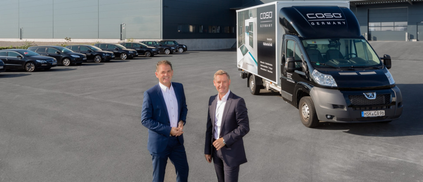 Zwei Männer stehen vor einem Transporter mit dem Logo von Caso Germany.