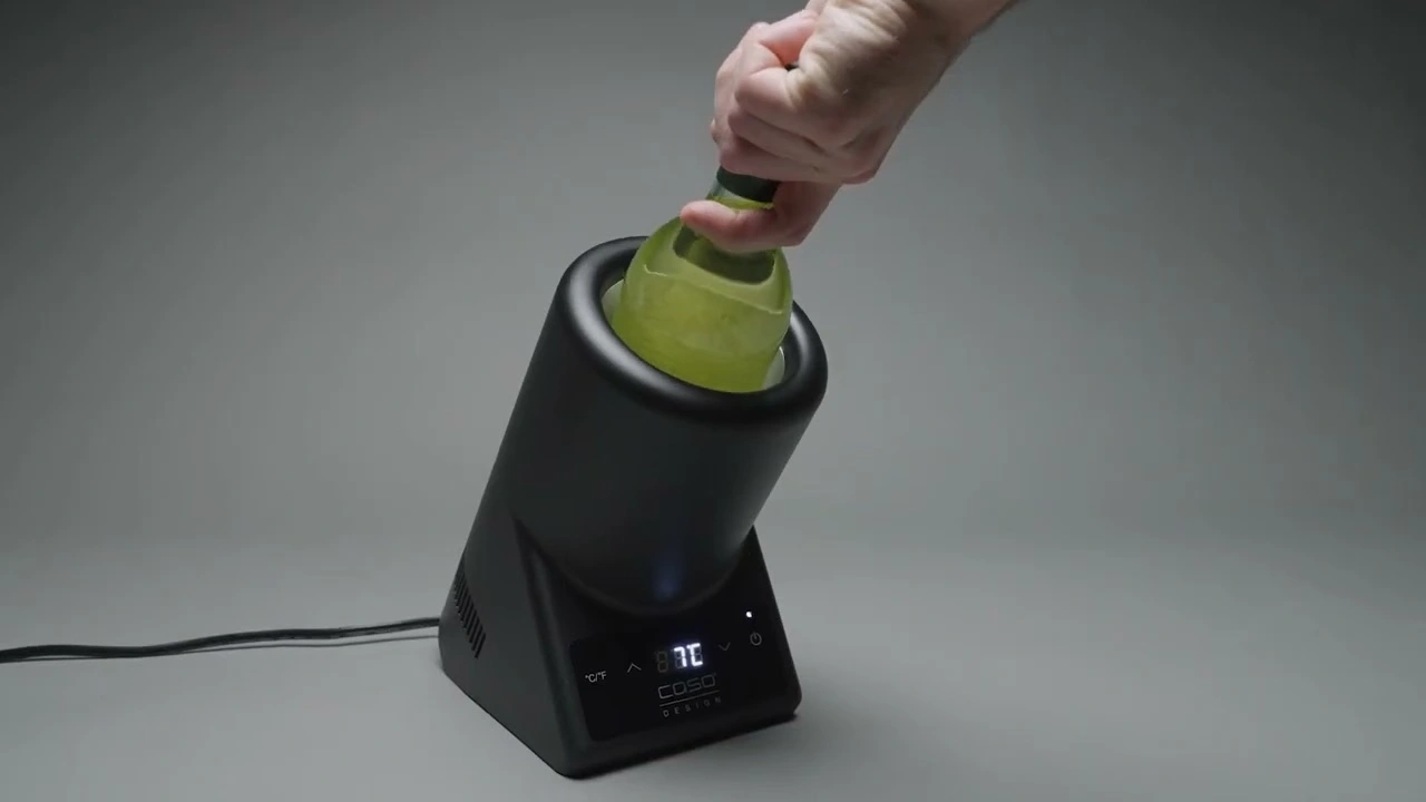 A person inserting a bottle into a black device to cool it down.