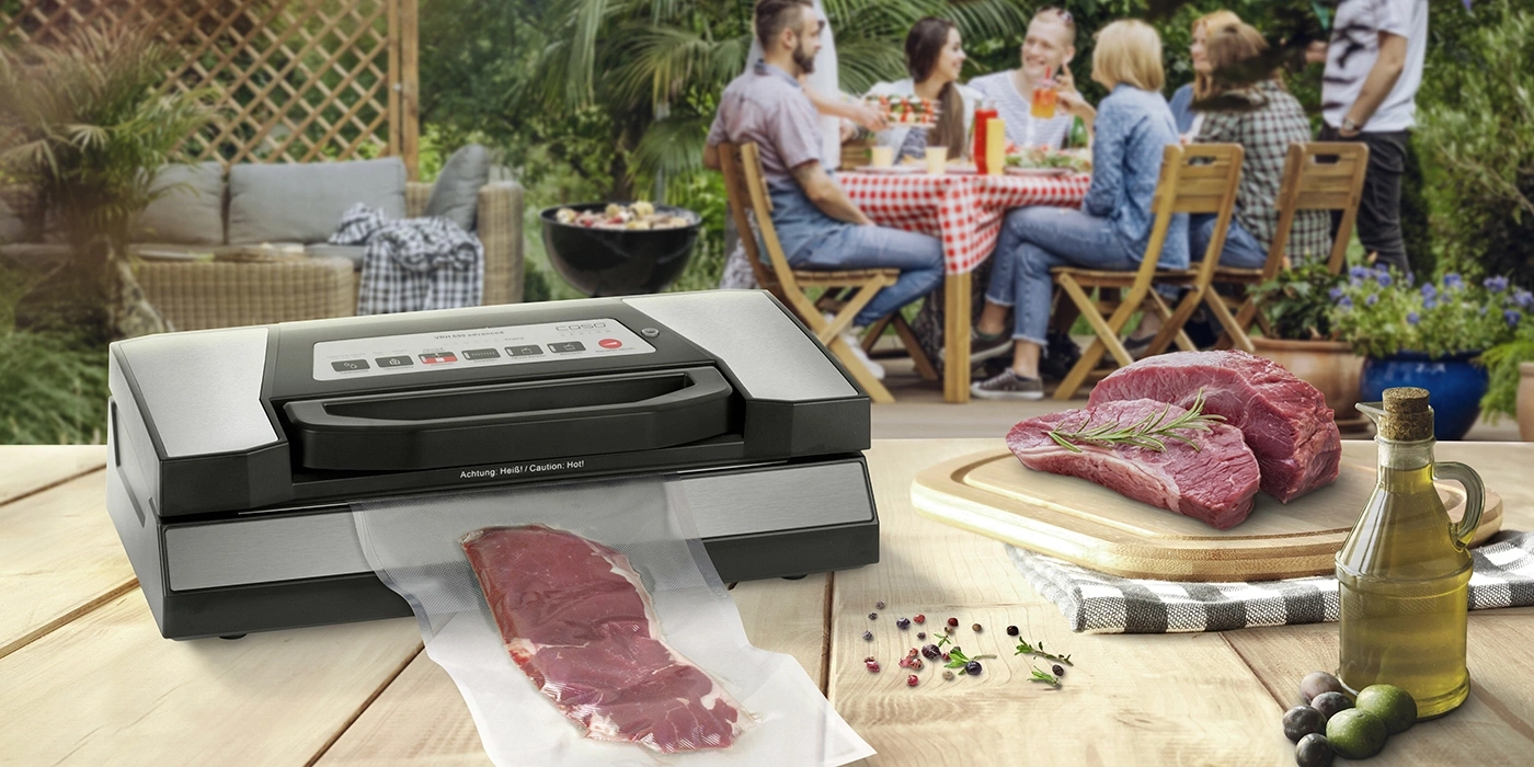 Ein Vakuumiergerät mit Fleisch und einer Gruppe von Menschen im Hintergrund.