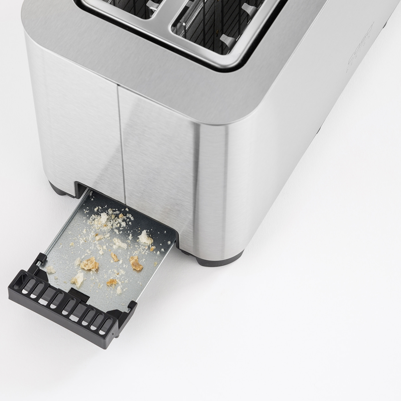 Toaster mit herausgezogener Krümelschublade und Brotkrümeln auf weißem Hintergrund.