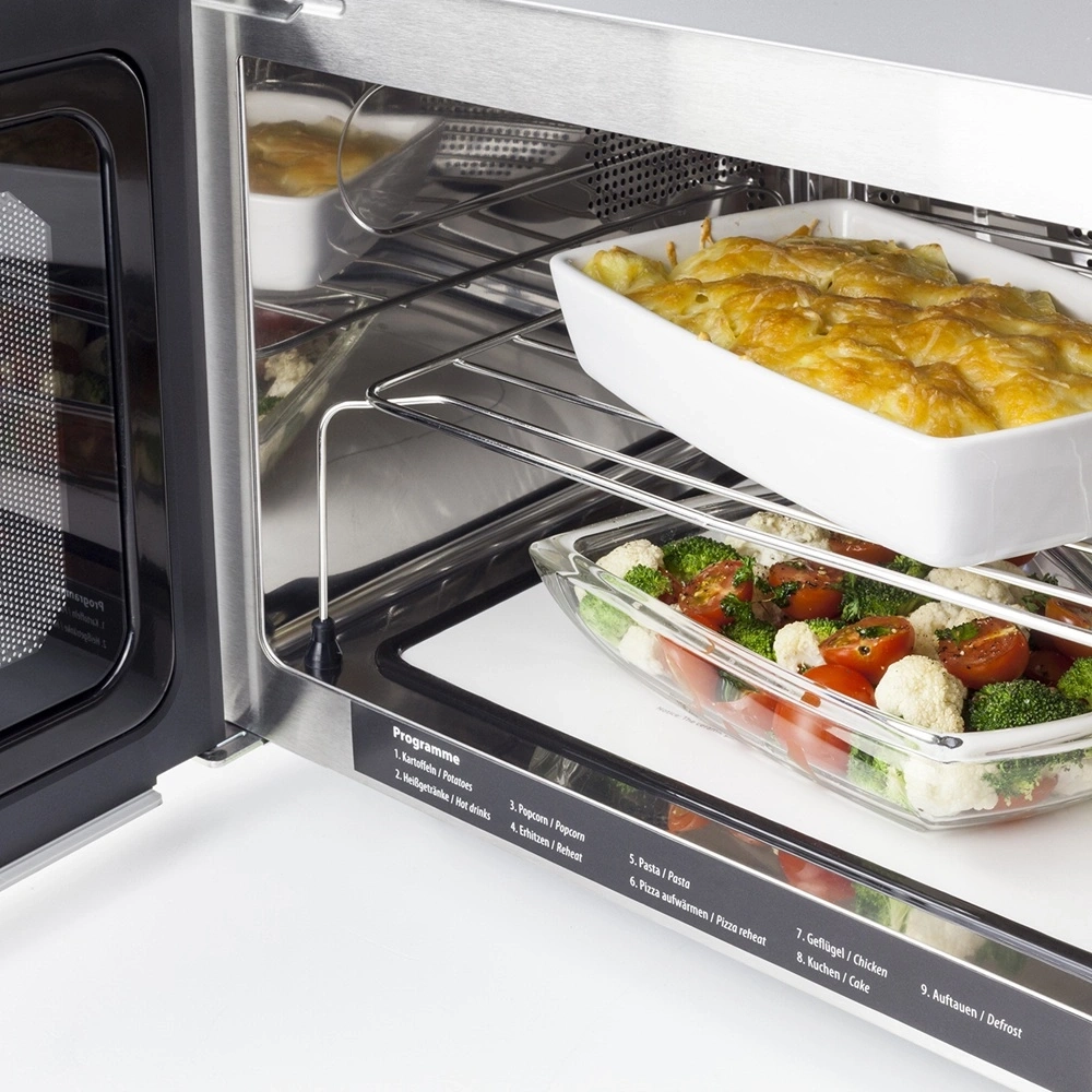 A modern built-in oven with two dishes being prepared on racks.