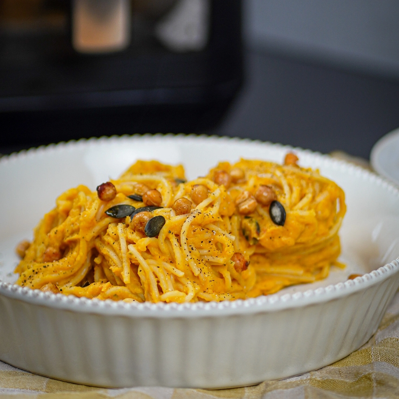 Spaghetti with pumpkin sauce and chickpeas, garnished with pumpkin seeds.