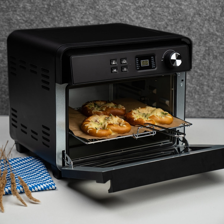 Black oven with open door and baked goods on a rack inside the oven