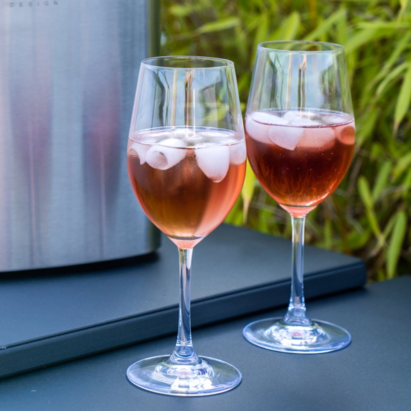 Two wine glasses with ice cubes on an outdoor table, close up