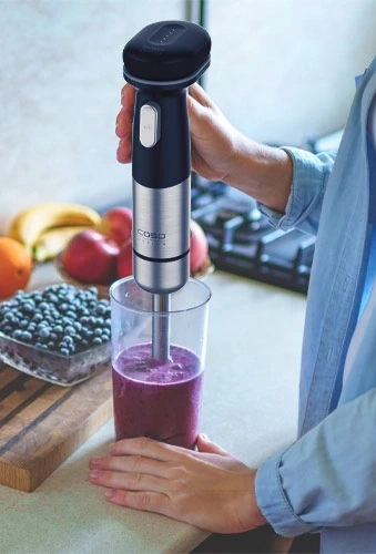 Person mixt Smoothie mit einem Stabmixer in einem Glas