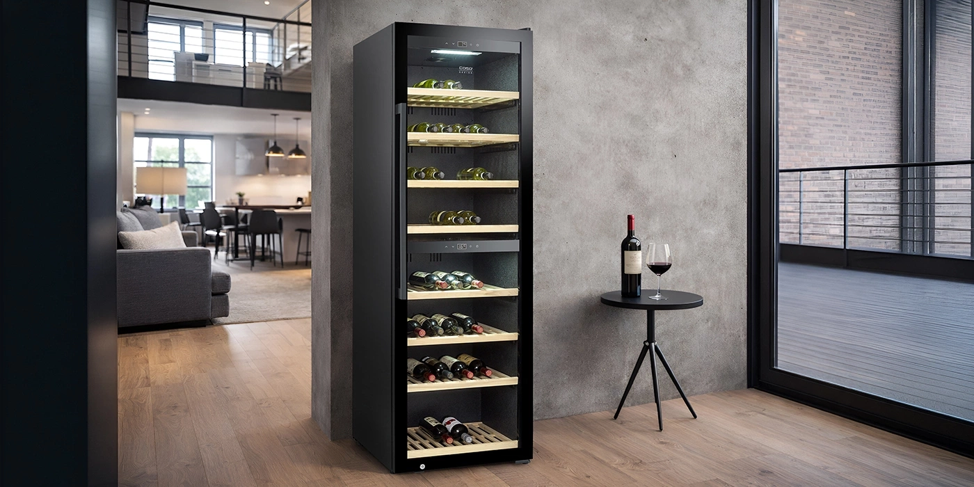 A modern wine cooler stocked with bottles and a glass of wine in a living room.