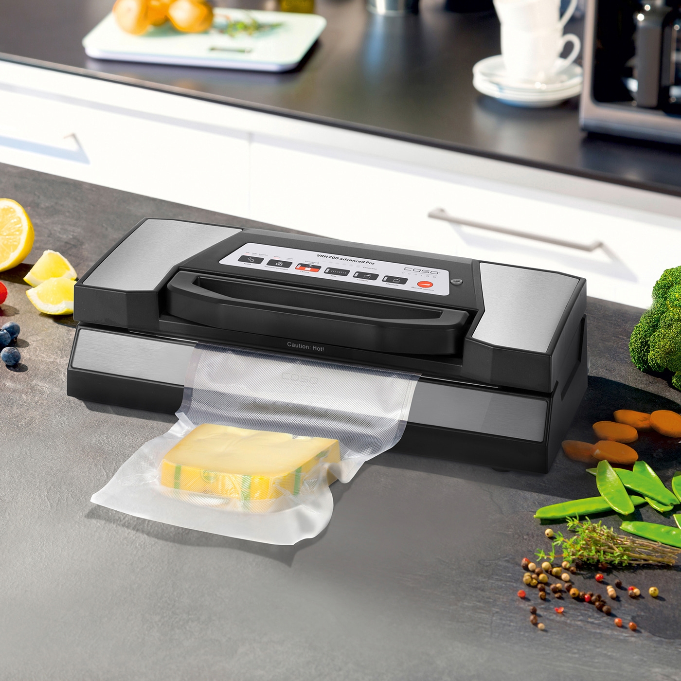 Vacuum sealer with cheese, vegetables, and spices on a kitchen countertop