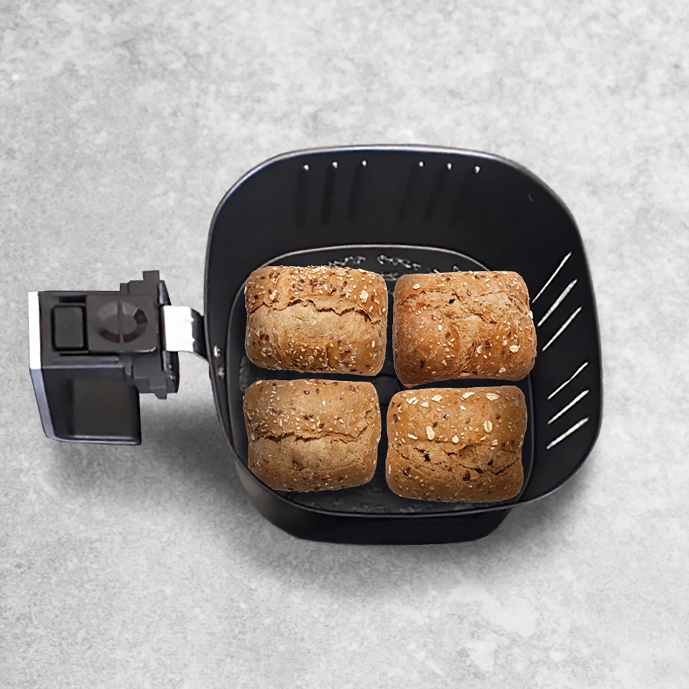 Air fryer with four rolls on gray background, close-up shot