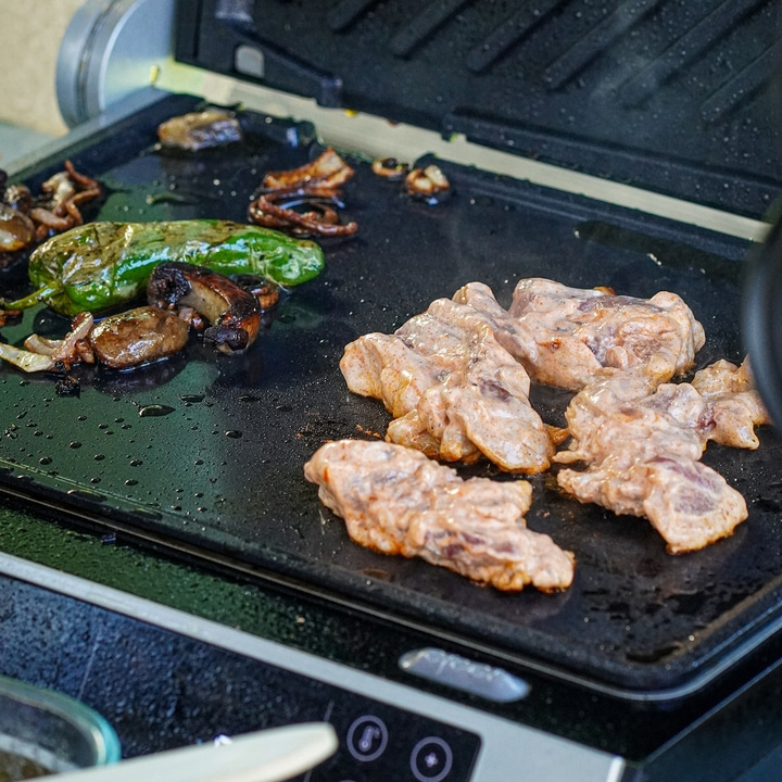 Gebratenes Steak mit Tomaten, Brot und Bier neben Vakuumiergerät.