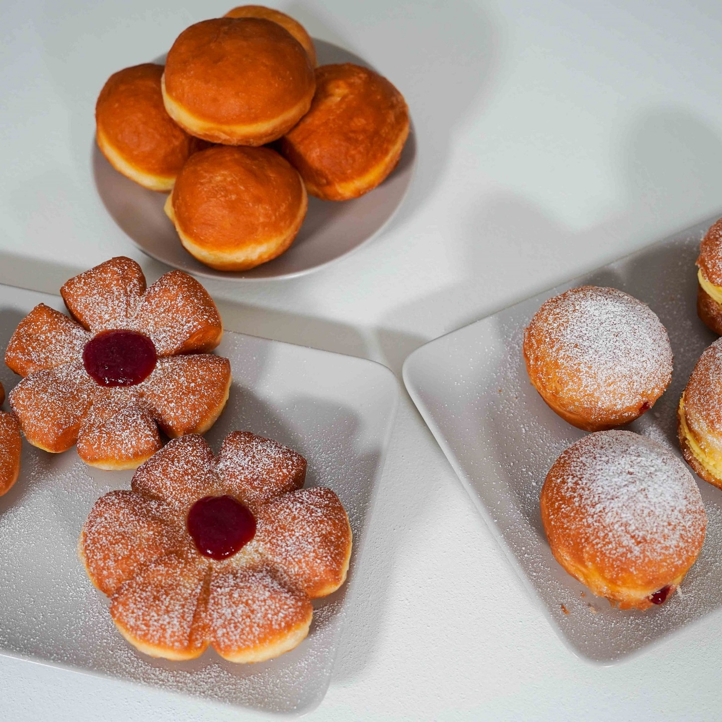 Delicious donuts on plates, with powdered sugar and jam, tasty and sweet dessert