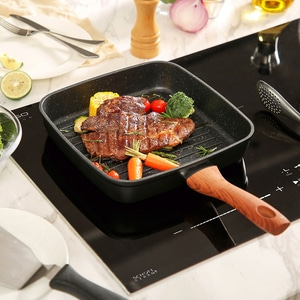 Grilled steak with vegetables in a pan on a stove top, ready to eat.