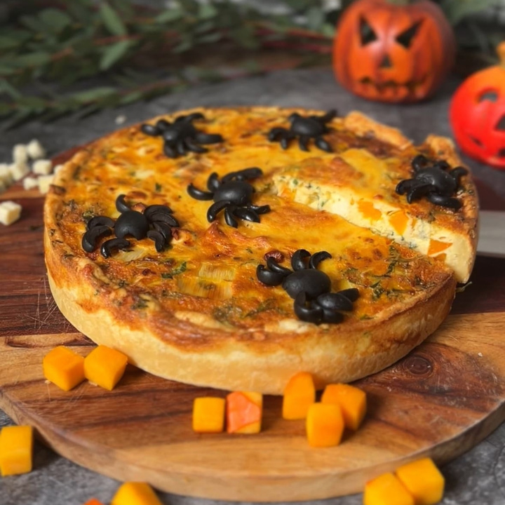 Kürbiskuchen mit Spinnen-Dekoration auf Holzbrett, Halloween-Konzept