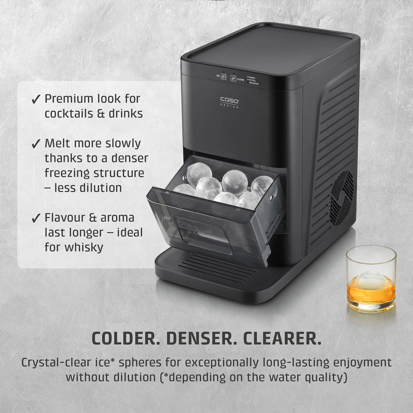 Ice maker with round ice cubes and a glass of whiskey next to it.