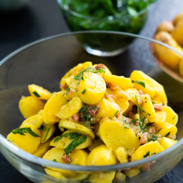 Potato salad in a glass bowl with herbs and bacon bits