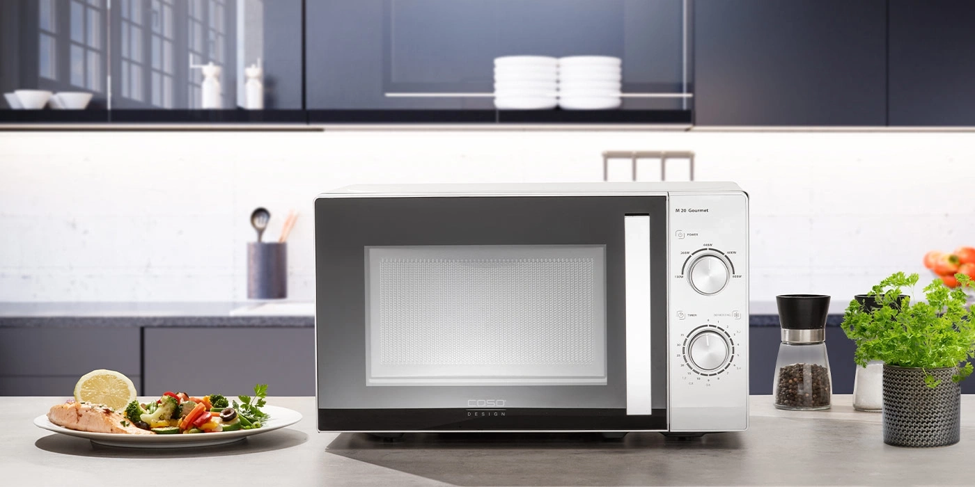 Microwave in a kitchen with food and decorations on the counter.