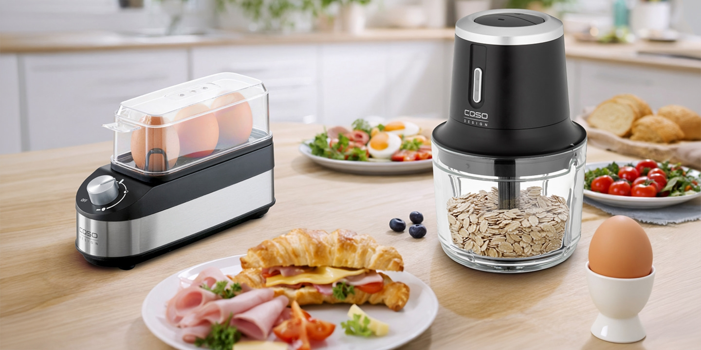 A breakfast scene with an egg cooker, chopper, and a croissant with ham and cheese.