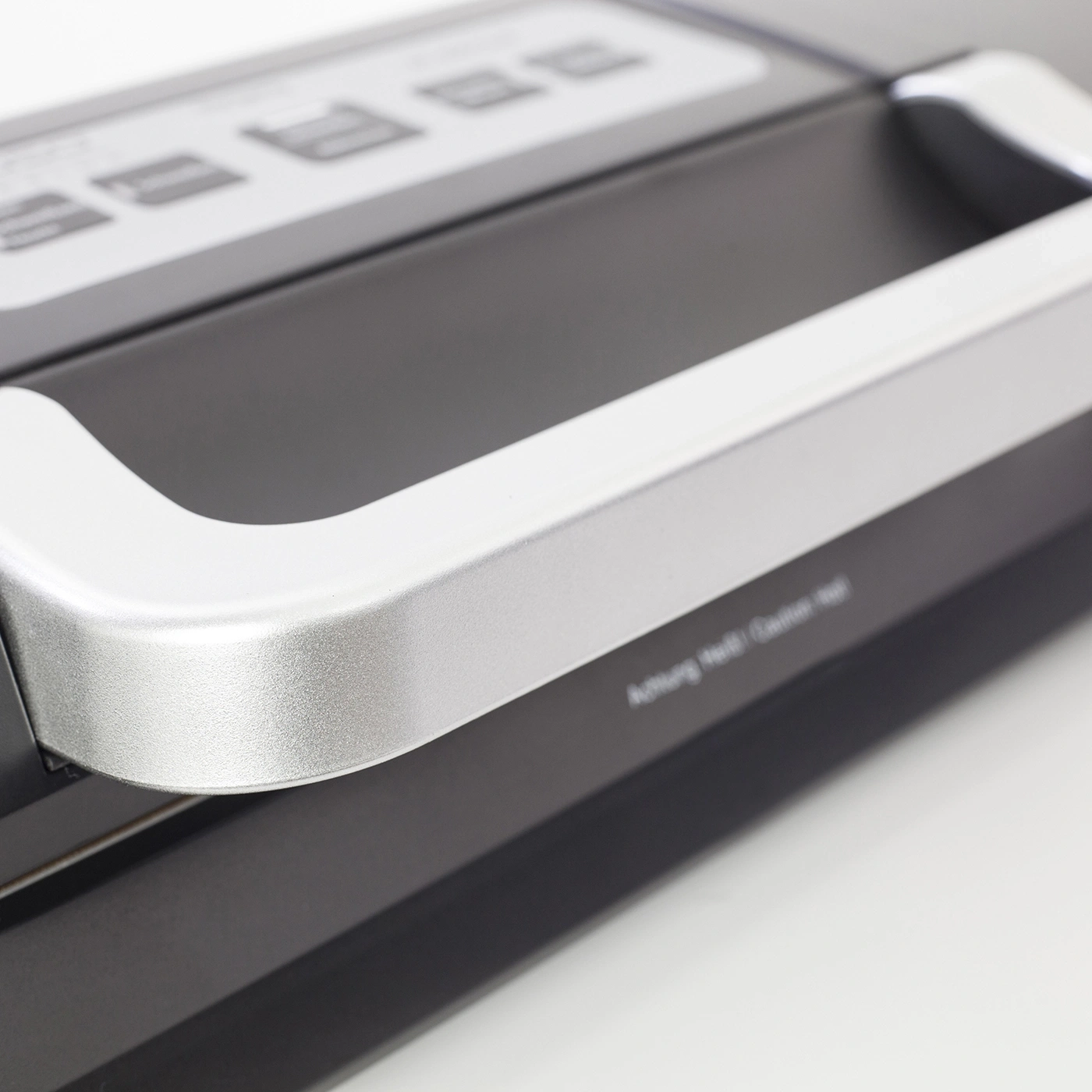Close-up of a black device with a silver handle and buttons on top.