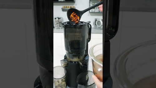 Person pouring ingredients into a juicer. Kitchen, appliance, food preparation.
