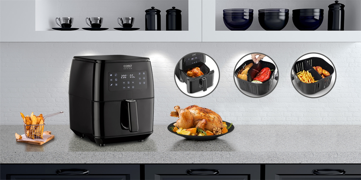 Schwarze Heißluftfritteuse mit Essen und Zubehör auf einer Küchenarbeitsplatte.