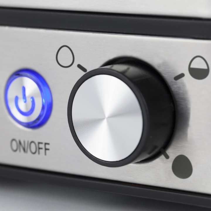 Close-up of a device with a knob and on/off button with blue light.