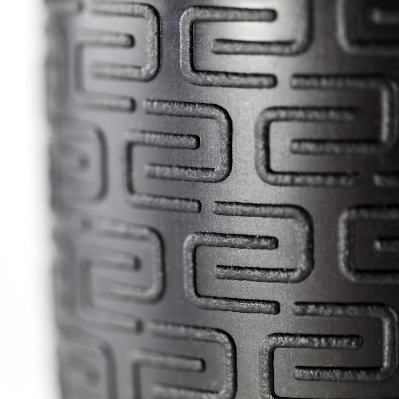 Close-up of a black object with engraved geometric patterns against a white background.