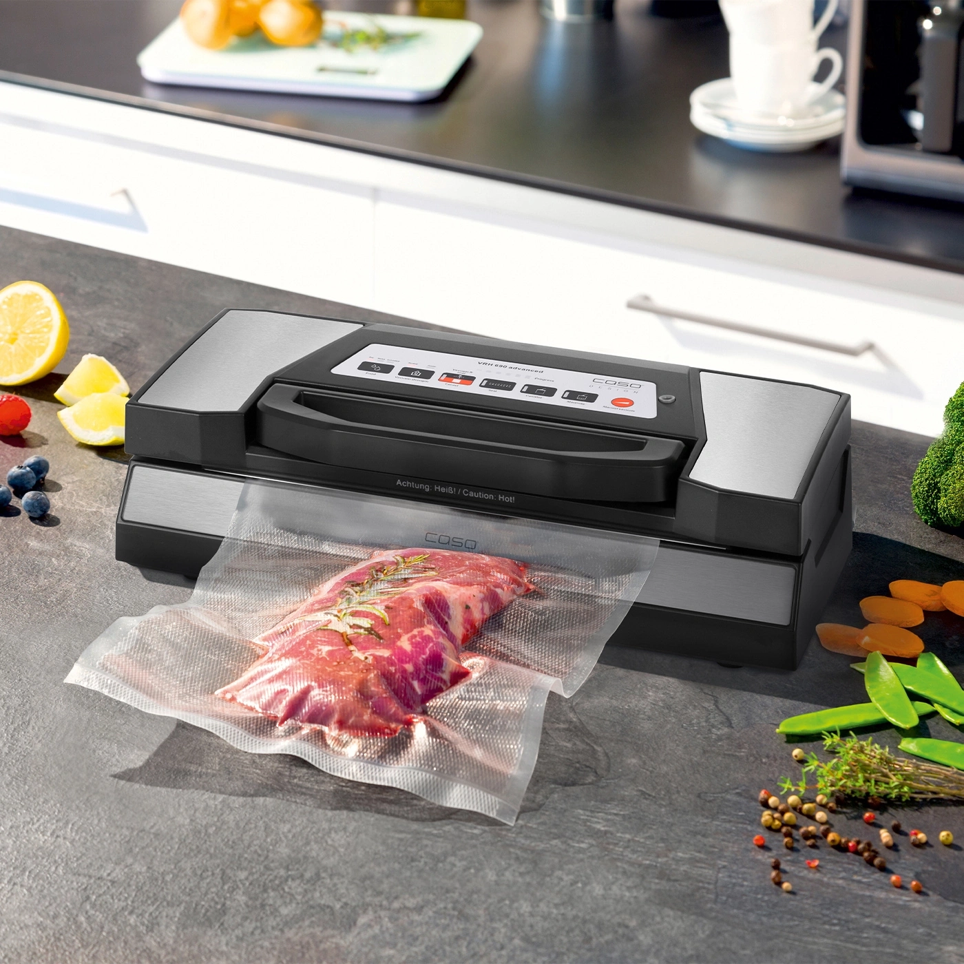 Vakuumiergerät mit Fleisch, Gemüse und Gewürzen auf einer Arbeitsplatte in der Küche.