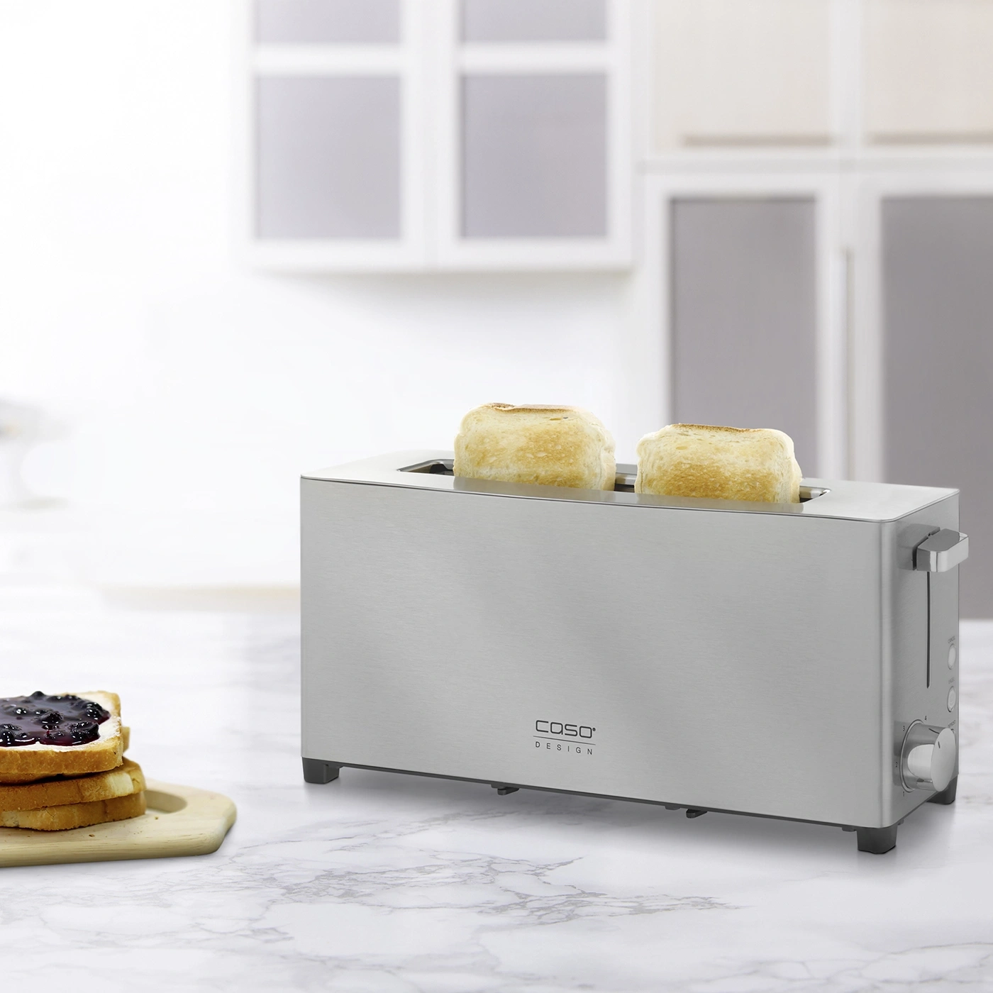 Ein Toaster mit zwei Toastbroten und Marmeladenbrot auf einem Brett.
