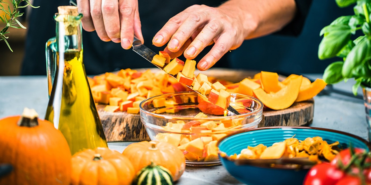 Pumpkin being cut. Hands cutting vegetables. Cooking. Preparing food. Close-up.