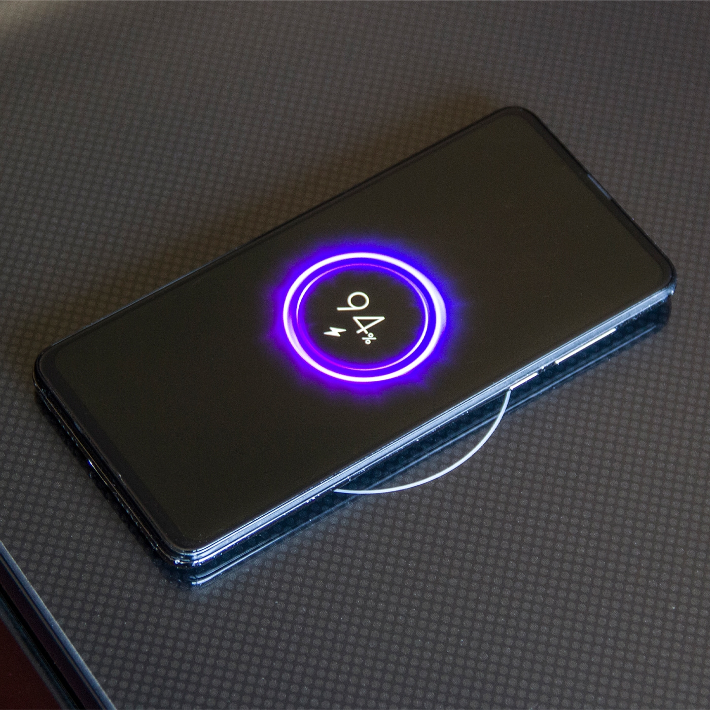 Smartphone charging wirelessly, 94%, on a black surface with a glowing circle.