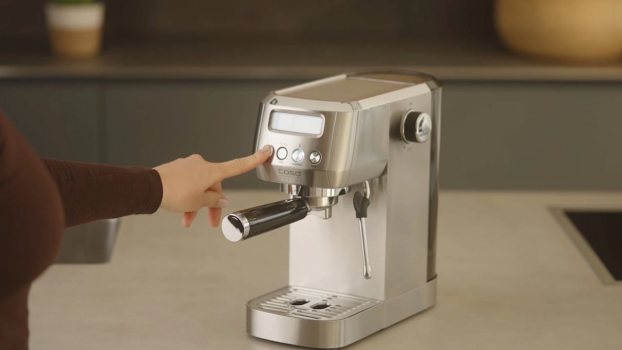 Person drückt Knopf an einer Espressomaschine, Nahaufnahme, Küche, Edelstahl