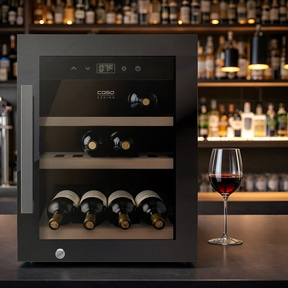 Ein moderner Weinkühlschrank mit Flaschen und einem Weinglas auf der Theke.