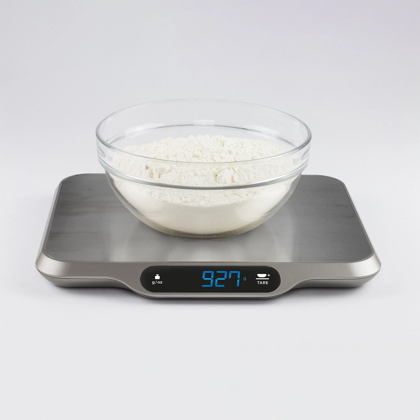 Scale with bowl and flour, showing 927 g, isolated on white background