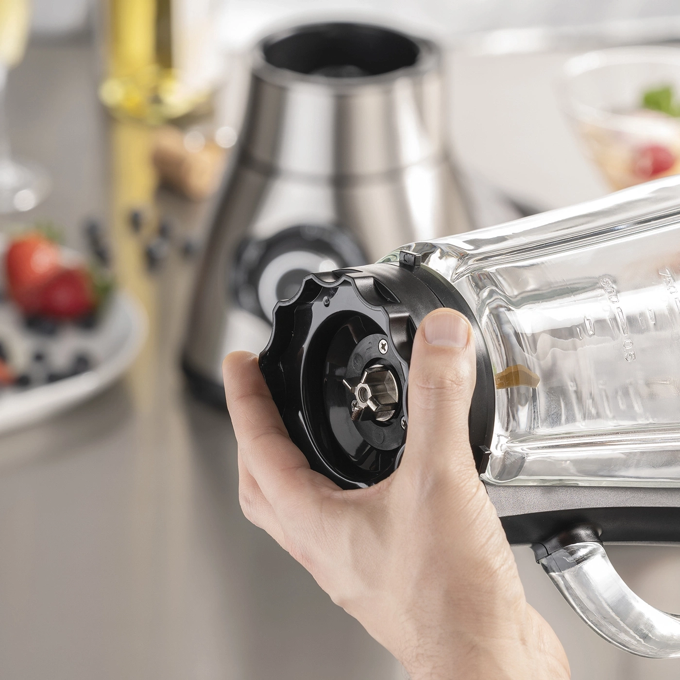 Close-up of a hand holding a blender with a blender in the background.