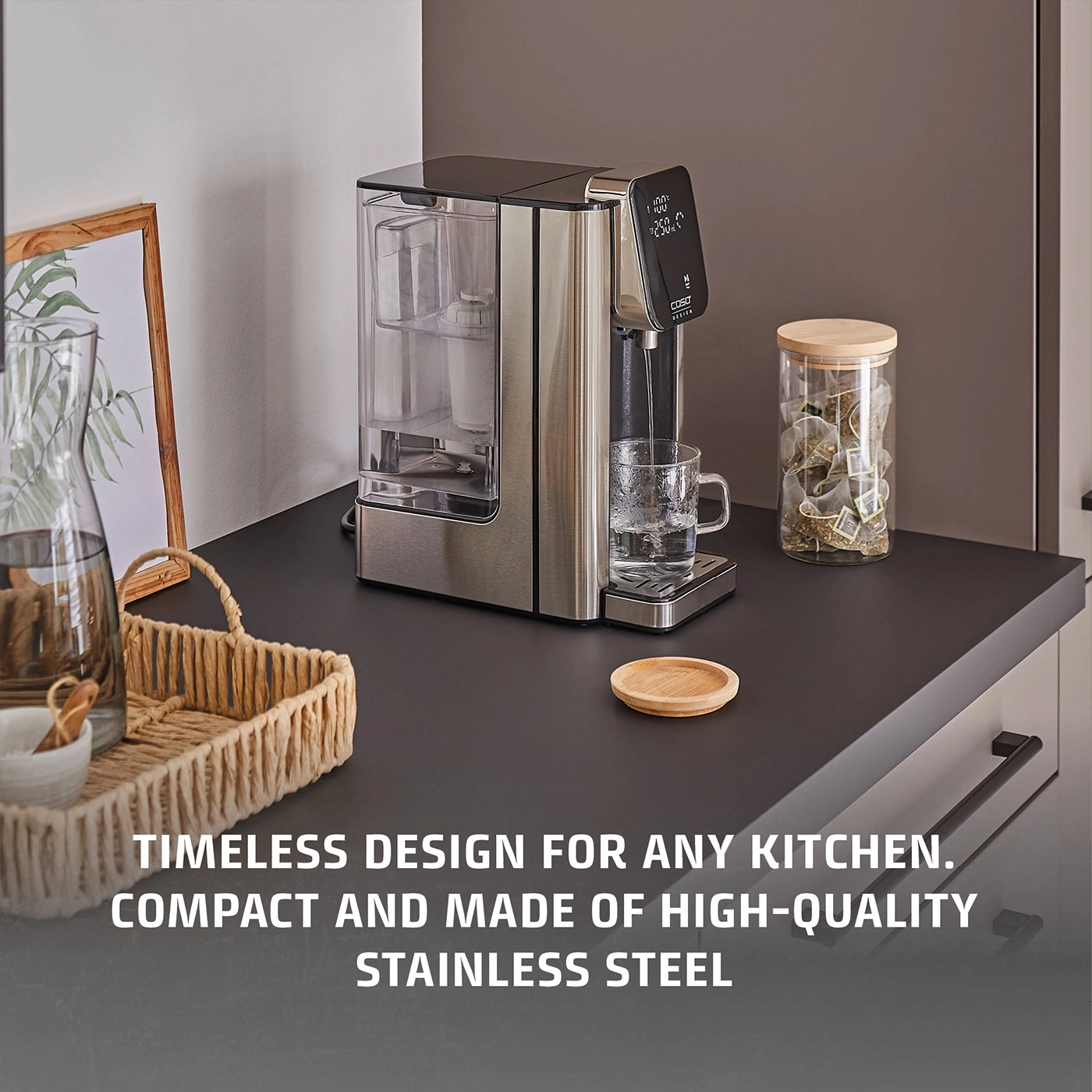 A water dispenser with a digital display and a glass of tea bags on a countertop.