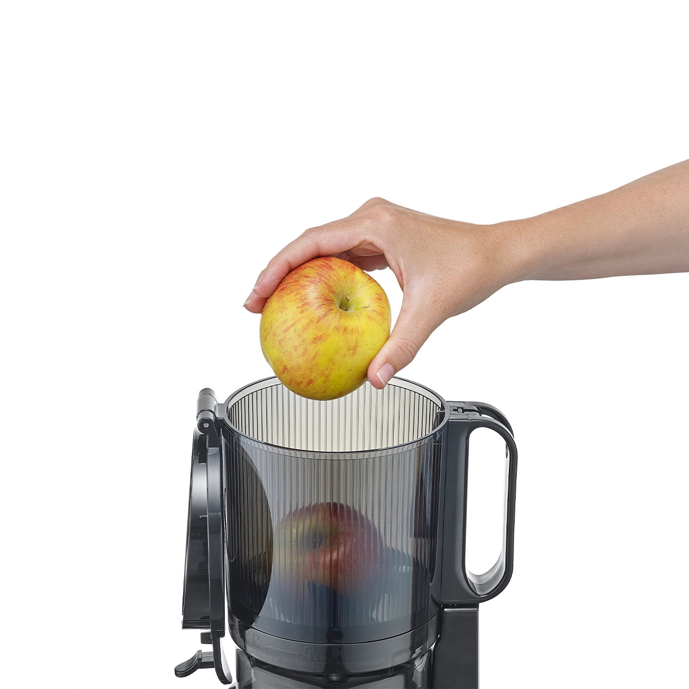 Hand placing apple into juicer. Preparing juice with fruit and kitchen appliance.
