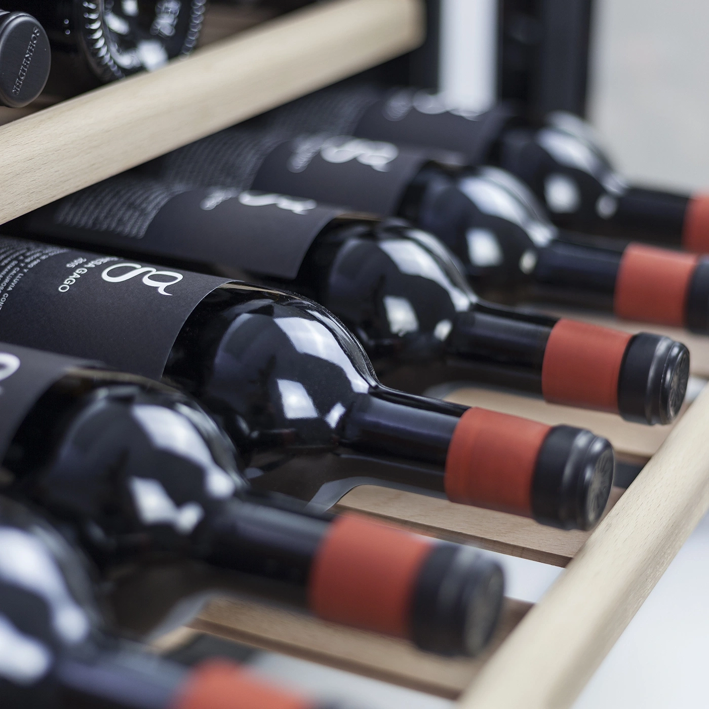 Close-up of wine bottles in a wine rack, red labels, wooden shelves