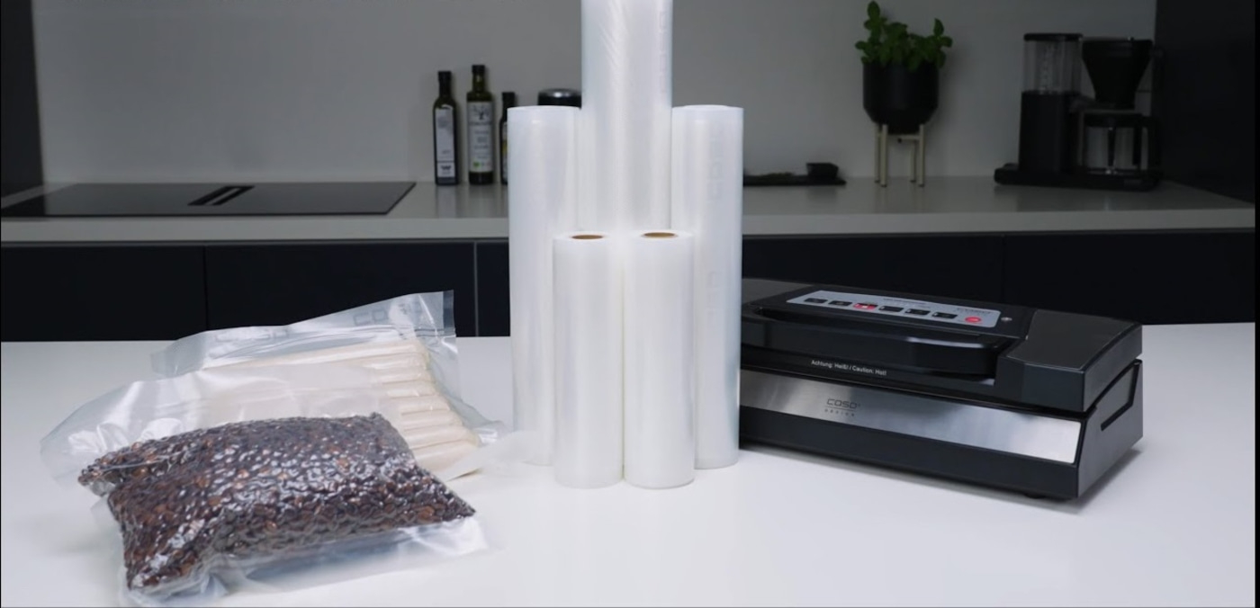 Vacuum sealer with rolls and packaged food on a white table