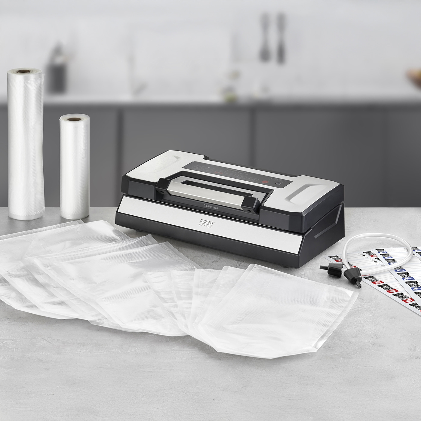 Vacuum sealer with accessories and bags on a gray surface.
