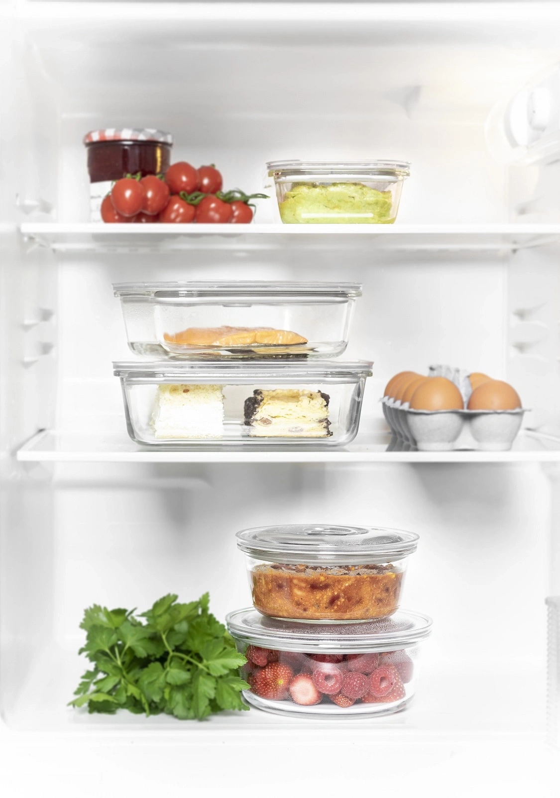 Kühlschrank mit Lebensmitteln: Tomaten, Eier, Kuchen, Lachs, Beeren, Kräuter und Aufstrich.