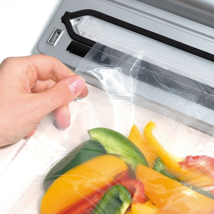 Person sealing vegetables in a vacuum sealer. Close-up of bell peppers.