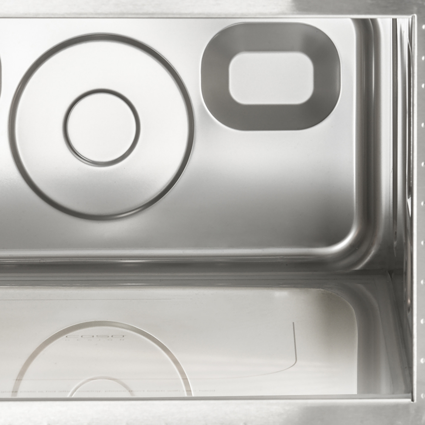 Stainless steel kitchen sink with circular and rectangular cutouts, close-up shot