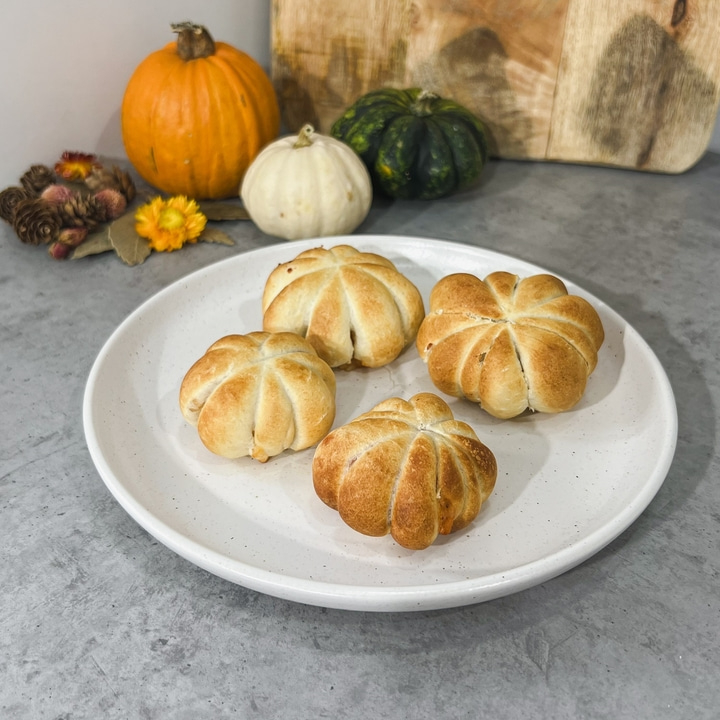 Teller mit Kürbisbrötchen, Kürbisse im Hintergrund, Herbstdekoration, Essen