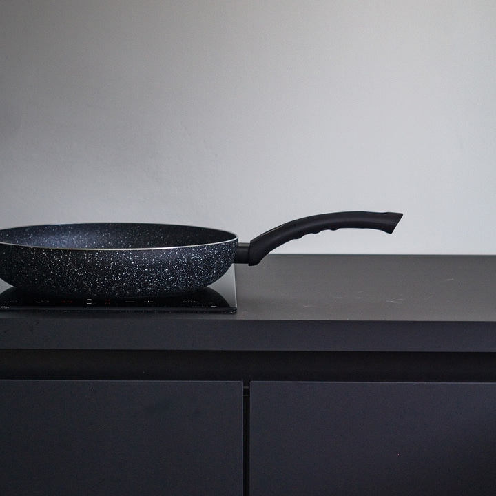 Frying pan on stove in dark kitchen, close-up shot