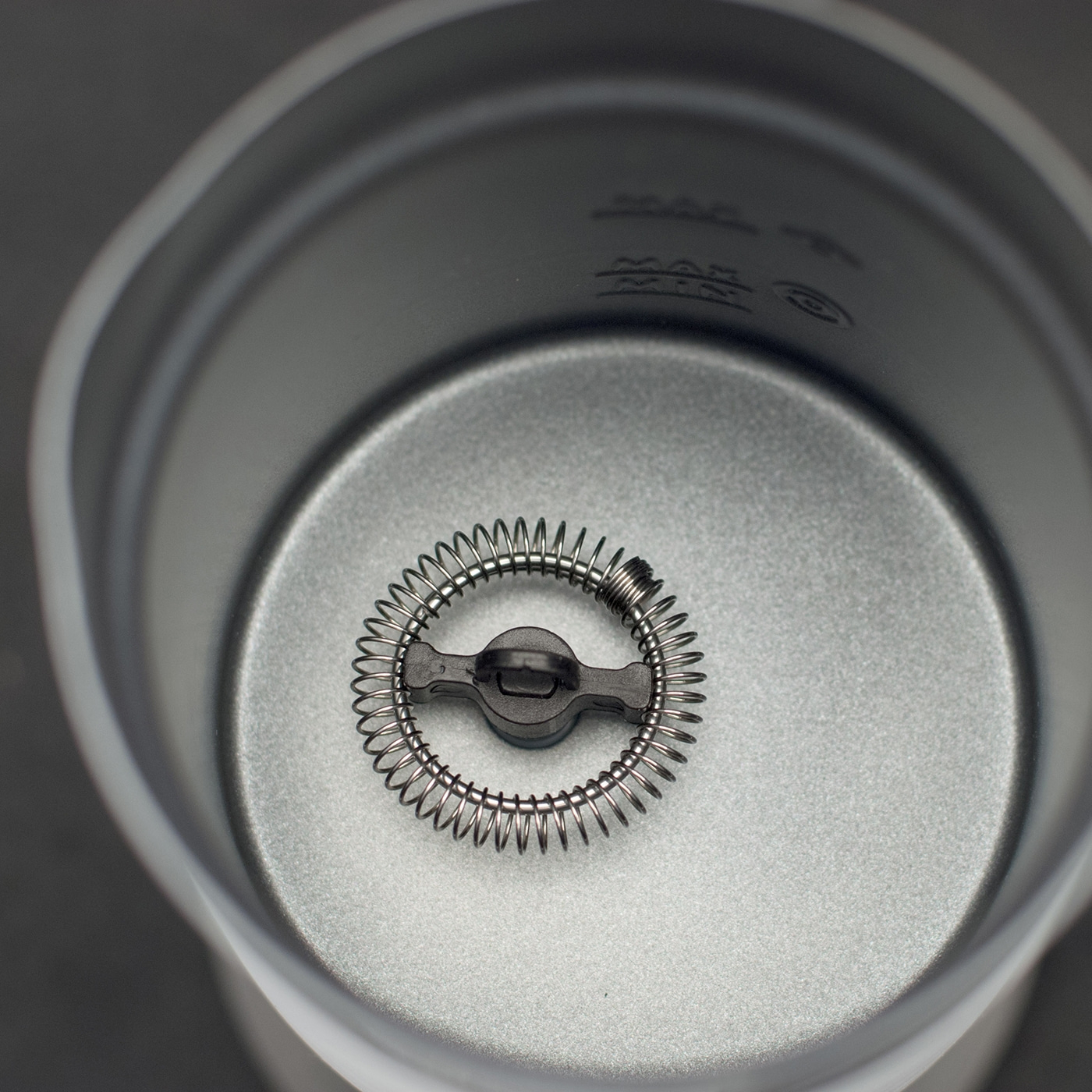 Close-up of a milk frother inside a container with some text