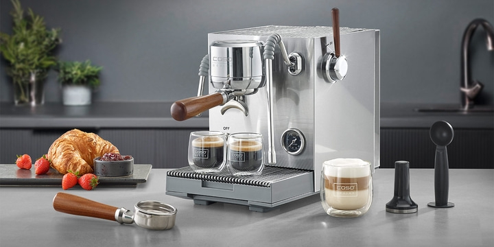 An espresso machine with coffee, croissant and strawberries.