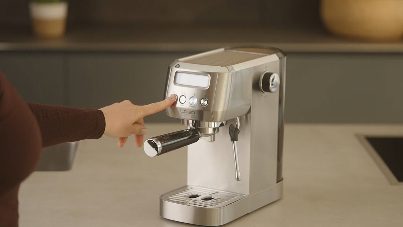 Person pressing button on espresso machine, close-up, kitchen, stainless steel