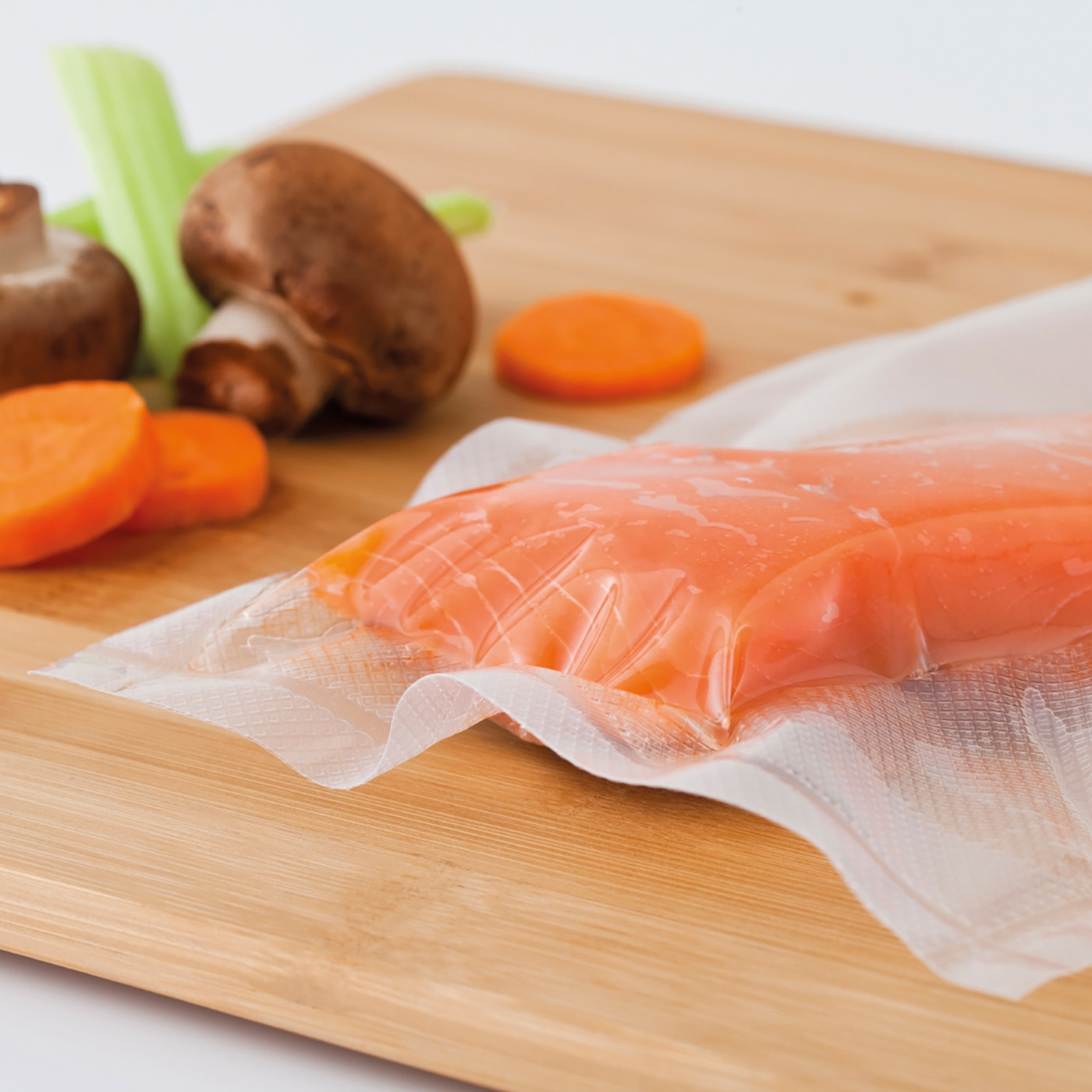 Salmon in plastic packaging on a wooden board with vegetables.