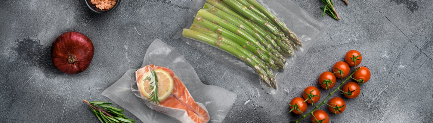 Fresh salmon, asparagus, tomatoes, and onion on a gray background.