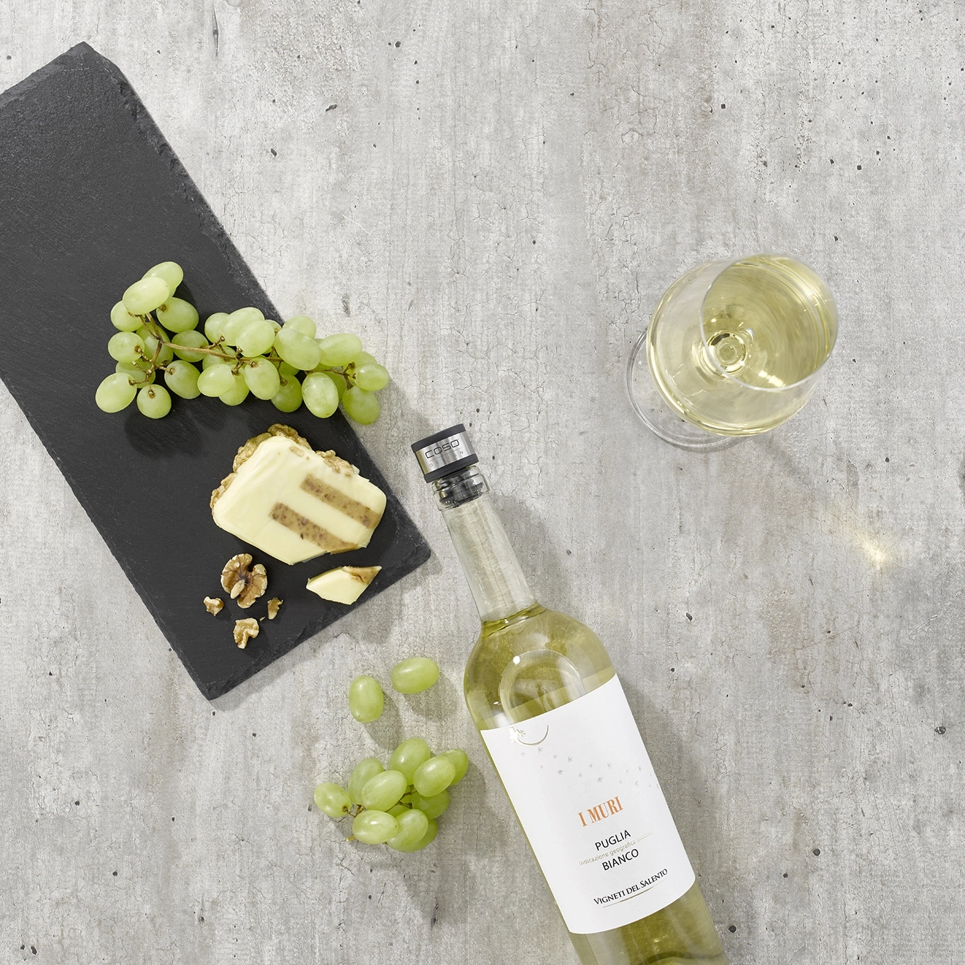 White wine, cheese, grapes, walnuts on slate, glass, bottle, table top