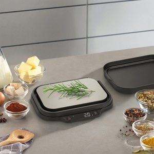 Kitchen scale with herbs and ingredients for cooking on a gray surface.